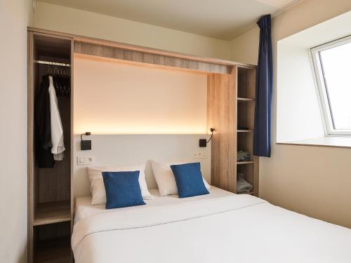 a bedroom with two beds with blue pillows at Holiday Suites Zeebrugge in Zeebrugge