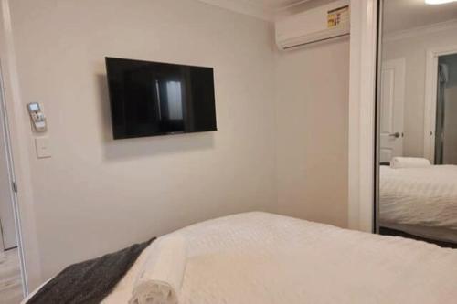 a room with a tv on a white wall at 2BR Wollongong Home 10mins walk to Hospital & Train Station with Free Parking and Fast Wi-Fi in Wollongong