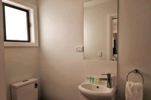 a bathroom with a sink and a toilet and a mirror at 2BR Wollongong Home 10mins walk to Hospital & Train Station with Free Parking and Fast Wi-Fi in Wollongong