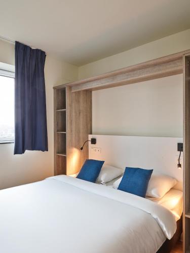 a bedroom with a large white bed with blue pillows at Holiday Suites Zeebrugge in Zeebrugge