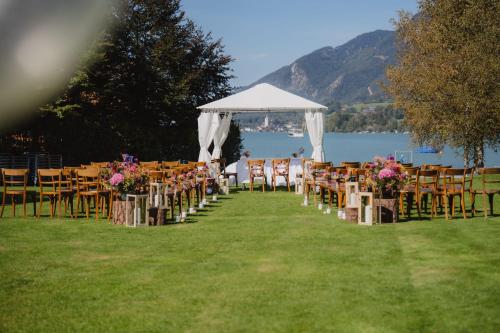 a row of tables and chairs with a white canopy at Seehotel Brandauer's Villen in Strobl
