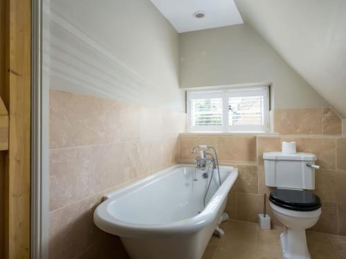 a bathroom with a white tub and a toilet at East Leaze in Chipping Campden