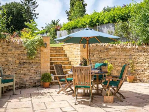 a patio with a table and chairs and an umbrella at East Leaze in Chipping Campden