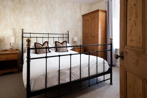 a bedroom with a black bed with white sheets and pillows at Driftwood Cottage by Coast & Country Stays in Seahouses
