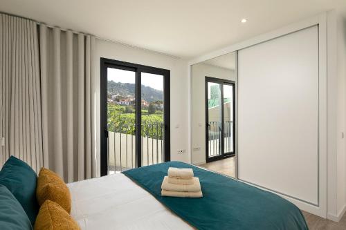 a bedroom with a bed with two towels on it at Marco 4 Seasons- Spring in Arco da Calheta