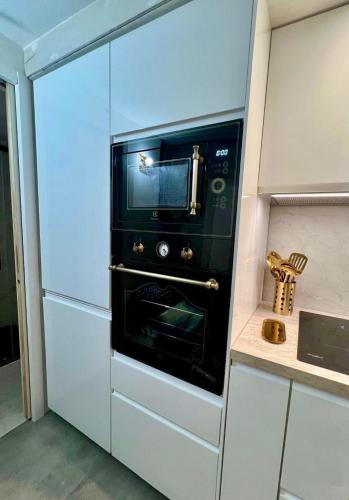 - un four micro-ondes noir dans une cuisine blanche dans l'établissement Typical Corsican Village House with Garden, à Calenzana