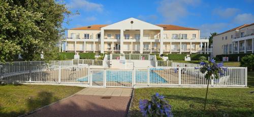 une clôture blanche avec une piscine en face d'un bâtiment dans l'établissement NOUVEAU - L'Orchidée, à deux pas de la plage et du lac, à Les Sables-dʼOlonne