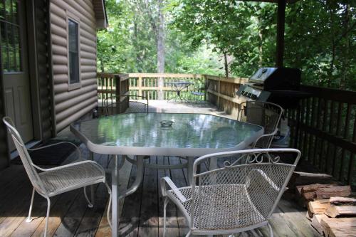 a table and chairs on a deck with a grill at Tree-Top Chalet in Logan