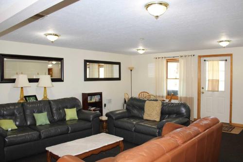 a living room with two leather couches and a table at Tree-Top Chalet in Logan