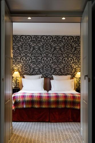 a bedroom with a large bed with a patterned wall at Le Pavillon de la Reine & Spa, Place des Vosges in Paris