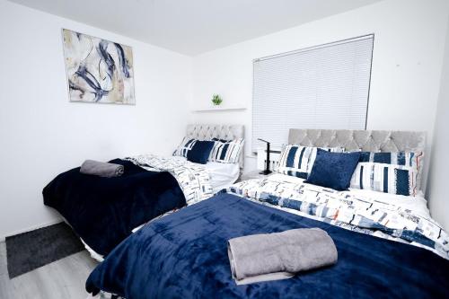 a bedroom with two beds with blue and white pillows at Cozy Place in Salford, Sleeps 8, 4 Bedroom, 5 Beds in Manchester
