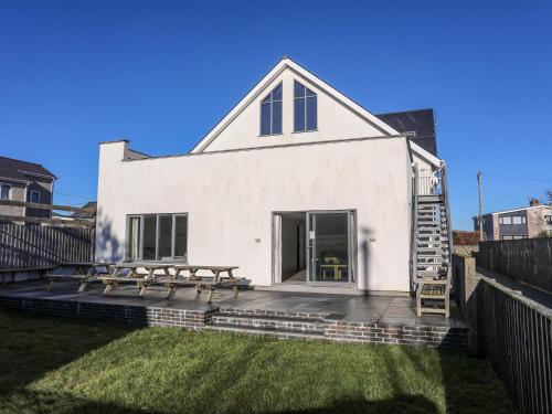 a white house with a picnic table on a deck at Plas Gwylan in Rhosneigr