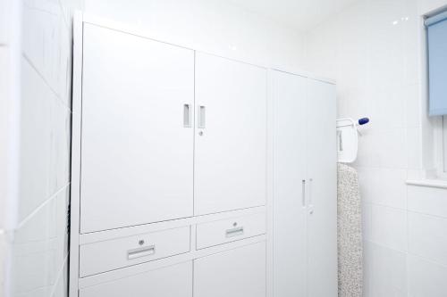 a white bathroom with white cabinets and a mirror at Cozy Place in Salford, Sleeps 8, 4 Bedroom, 5 Beds in Manchester