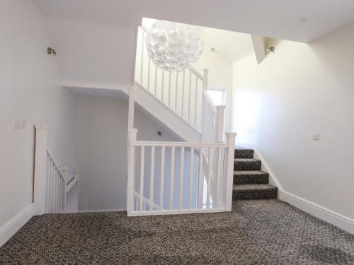 a white staircase in a room with white walls at Plas Gwylan in Rhosneigr