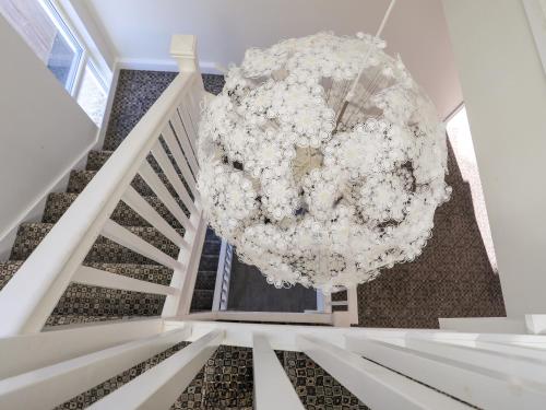 a large white chandelier hanging from a staircase at Plas Gwylan in Rhosneigr