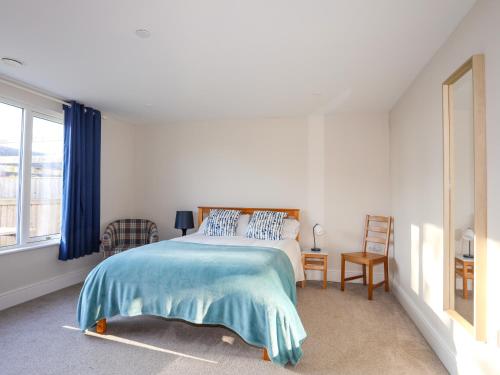 a white bedroom with a bed and a window at Plas Gwylan in Rhosneigr