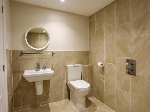 a bathroom with a toilet and a sink and a mirror at Plas Gwylan in Rhosneigr