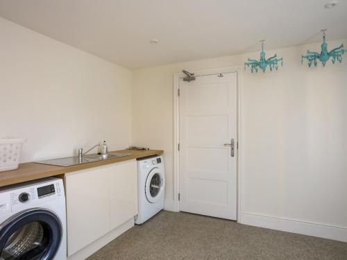 a white laundry room with a washer and dryer at Plas Gwylan in Rhosneigr