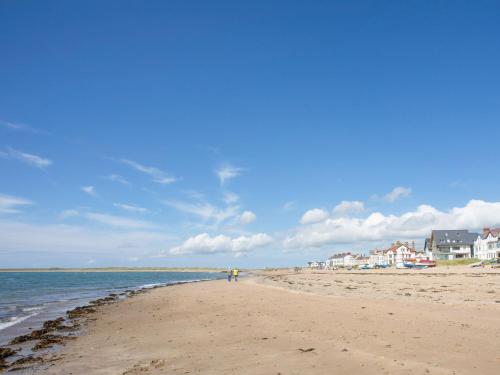 a person standing on a beach near the water at Plas Gwylan in Rhosneigr