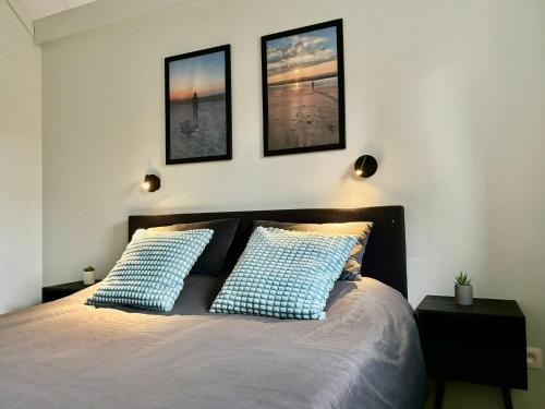 a bedroom with a bed with three pictures on the wall at Vitamin Sea in Oostduinkerke