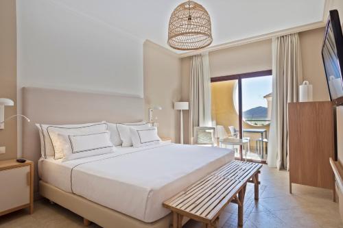 a bedroom with a large white bed with a bench at Melia Villaitana in Benidorm