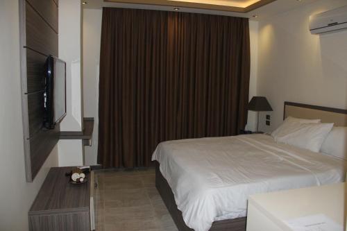 a bedroom with a bed and a flat screen tv at Seven Days Hotel in Irbid