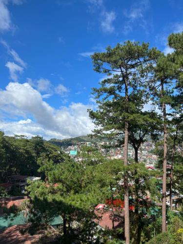 a view of a city from behind some trees at 163 Sqm Luxury Spacious Modern European Cott-age Style 3 Bedrooms With 2 Parkings in Baguio