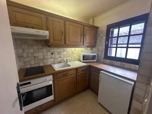 une cuisine avec des armoires en bois et un évier dans l'établissement Grande Maison de village climatisée avec cours., à Saintes-Maries-de-la-Mer