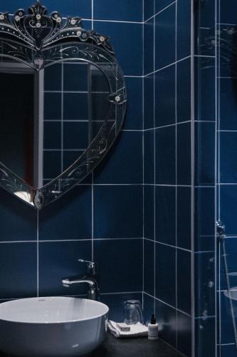 a blue tiled bathroom with a sink and a mirror at Hôtel du Petit Moulin, Haute Couture hotel by Lacroix in Paris