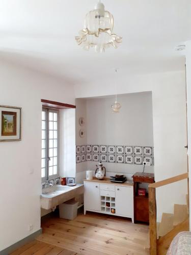 La salle de bains blanche est pourvue d'un lavabo et d'un lustre. dans l'établissement Maison d'Orion, à La Réole