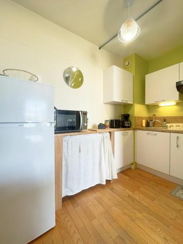  La cuisine est équipée de placards blancs et d'un réfrigérateur. dans l'établissement Appartement spacieux avec balcon à Bourg en Bresse, à Bourg-en-Bresse