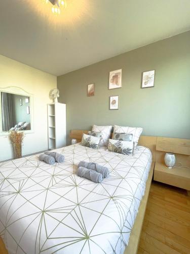 une chambre avec un grand lit avec des oreillers dessus dans l'établissement Appartement spacieux avec balcon à Bourg en Bresse, à Bourg-en-Bresse