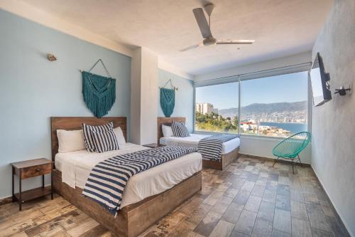 a bedroom with two beds and a large window at LUXO Casa en Acapulco Zona Brisas Guitarrón con vistas espectaculares y 2 albercas in Acapulco