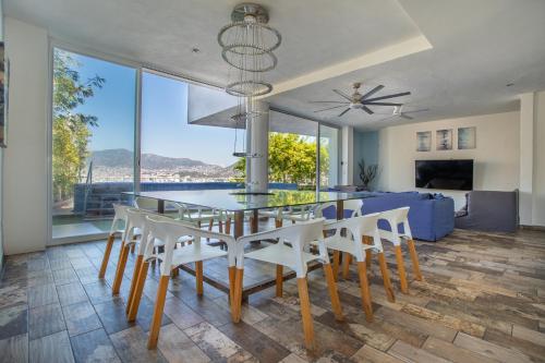 a dining room with a glass table and white chairs at LUXO Casa en Acapulco Zona Brisas Guitarrón con vistas espectaculares y 2 albercas in Acapulco
