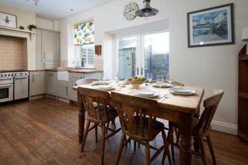 a kitchen with a large wooden table and chairs at Pebble Cottage by Coast & Country Stays in Seahouses
