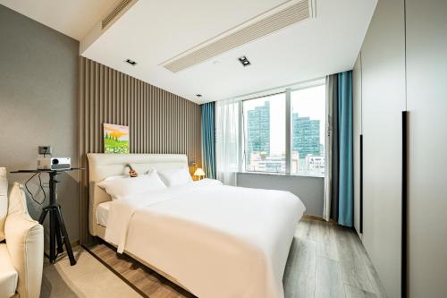 a bedroom with a white bed and a large window at Today Aparthotel West Lujiazui Shanghai in Shanghai