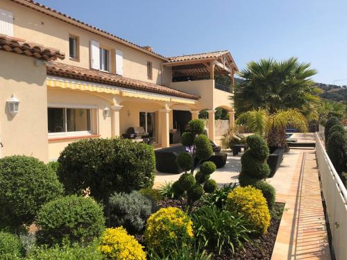une maison avec un jardin planté d'arbres et de buissons dans l'établissement Villa Joya climatisée pour 8 personnes avec piscine et vue mer à La Londe-Les-Maures, à La Londe-les-Maures