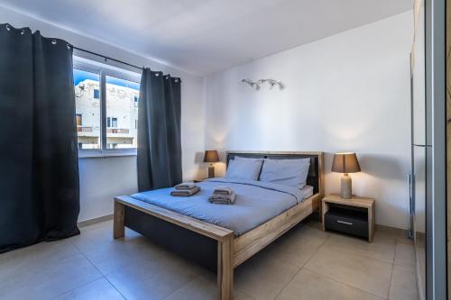 a bedroom with a bed with blue sheets and a window at Bright and modern apartment in St Julian's