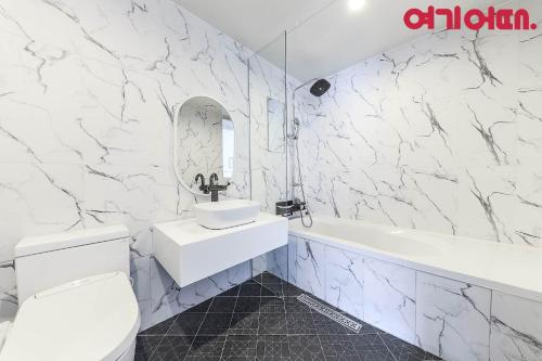 a bathroom with a sink and a toilet and a tub at Gwanganri HOTEL OCEANVIEW in Busan