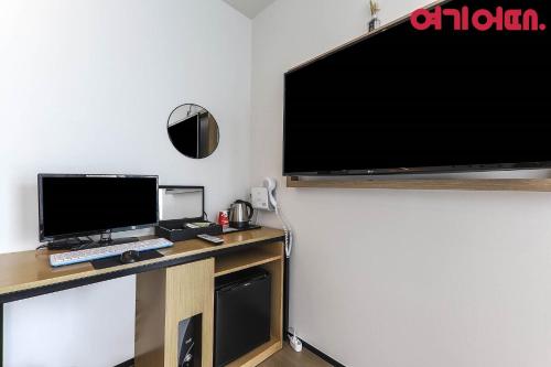 a desk with a computer and a television on a wall at Gwanganri HOTEL OCEANVIEW in Busan
