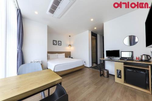 a hotel room with a bed and a desk and a table at Gwanganri HOTEL OCEANVIEW in Busan