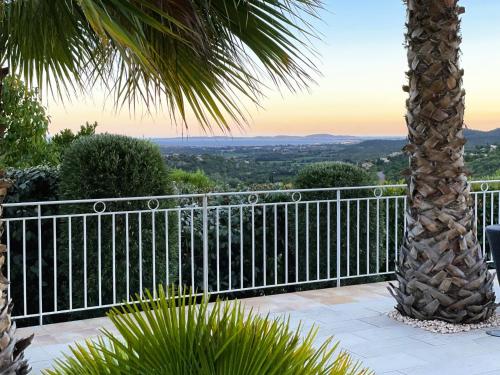 d'un balcon avec une clôture et un palmier. dans l'établissement Villa Joya climatisée pour 8 personnes avec piscine et vue mer à La Londe-Les-Maures, à La Londe-les-Maures