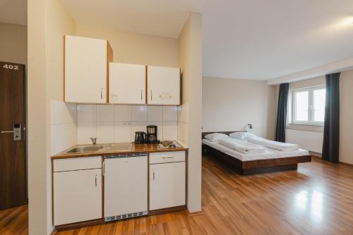 a kitchen with white cabinets and a bed in a room at Wombat's City Hostel Leipzig in Leipzig