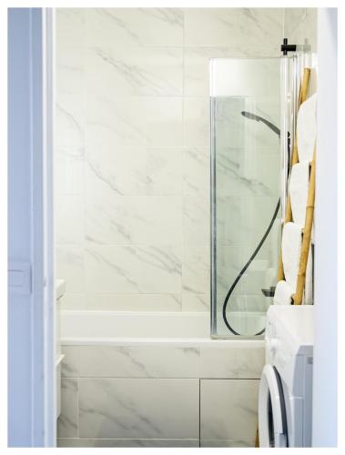 La salle de bains est pourvue d'une douche en marbre blanc. dans l'établissement Joli 3 pièces à 100m du métro, proche de Paris, à Pantin