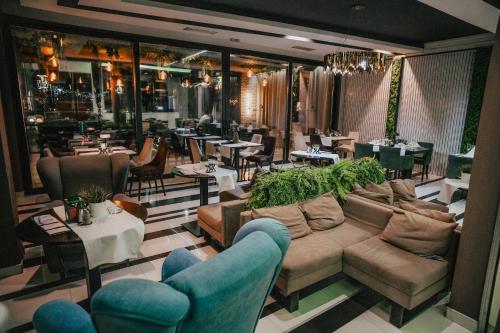 a restaurant with couches and tables and a restaurant with tables and chairs at Hotel Bavka in Leskovac