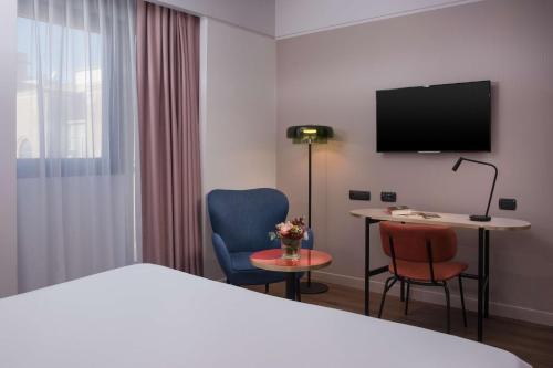 a hotel room with a bed and a desk and a tv at NH Catania Centro in Catania
