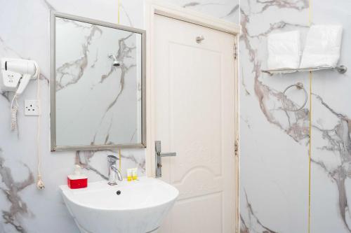 a white bathroom with a sink and a mirror at Collection O Muscat Airport Hotel Apartments in Ghursheba