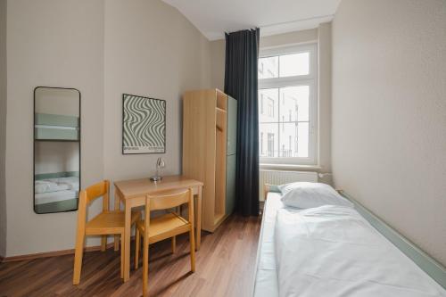 a bedroom with a bed and a desk and a table at Wombat's City Hostel Leipzig in Leipzig