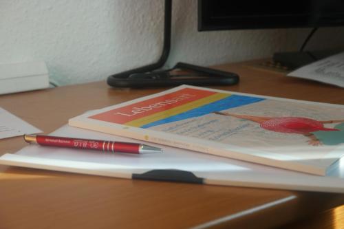a book and a pen sitting on a desk at Hotel Merlin Garni in Cologne