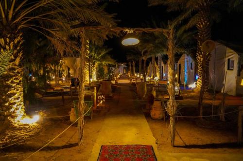 a resort with palm trees and lights at night at Sahara Garden Luxury Camp in Merzouga